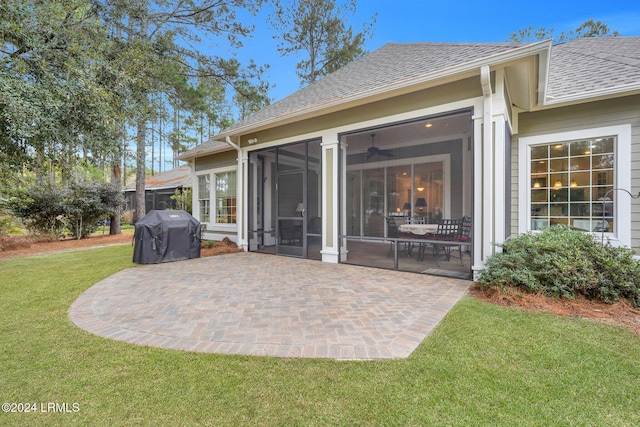 back of property with a lawn, a sunroom, a patio, and ceiling fan