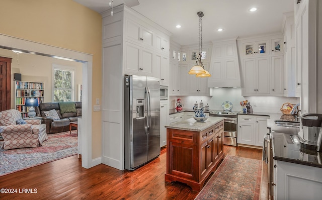 kitchen with custom exhaust hood, a center island, hanging light fixtures, appliances with stainless steel finishes, and white cabinets