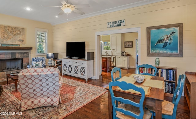 living room with ceiling fan, dark hardwood / wood-style flooring, a tile fireplace, and wood walls