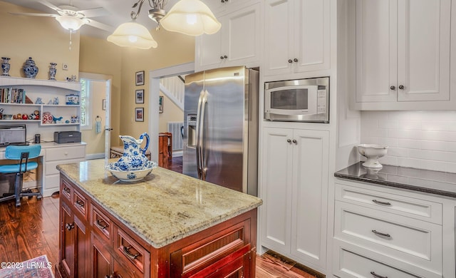 kitchen with built in microwave, stainless steel fridge with ice dispenser, hanging light fixtures, dark hardwood / wood-style floors, and backsplash