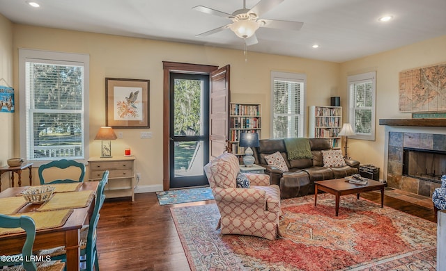 living room featuring ceiling fan, a fireplace, dark hardwood / wood-style floors, and a healthy amount of sunlight