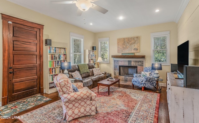 living room featuring a tile fireplace, dark hardwood / wood-style floors, and ceiling fan