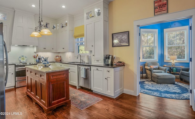 kitchen with a kitchen island, appliances with stainless steel finishes, sink, white cabinets, and hanging light fixtures