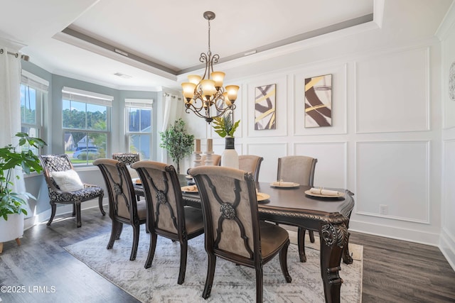 dining area featuring ornamental molding, a notable chandelier, dark hardwood / wood-style flooring, and a tray ceiling