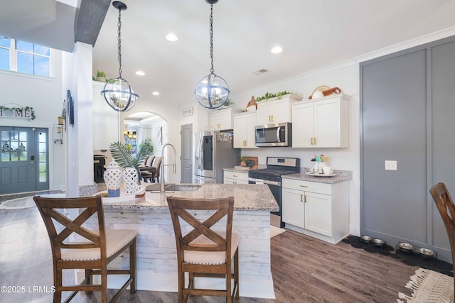 kitchen featuring sink, white cabinetry, light stone counters, hanging light fixtures, and appliances with stainless steel finishes