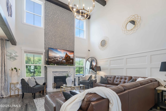 living room with a notable chandelier, a towering ceiling, wood-type flooring, and a premium fireplace