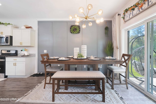 dining area featuring wood-type flooring, ornamental molding, and a chandelier