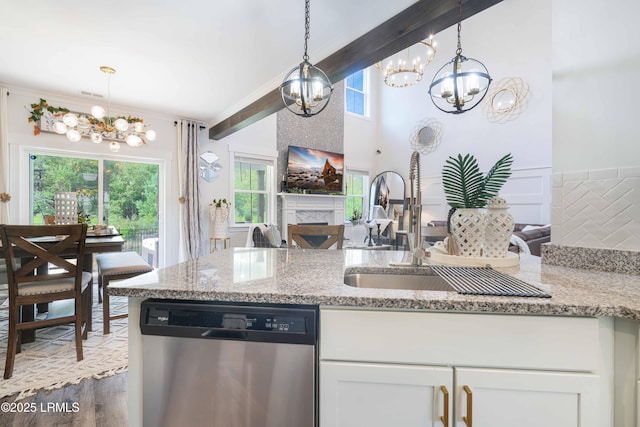 kitchen featuring pendant lighting, dishwasher, white cabinetry, beam ceiling, and light stone counters