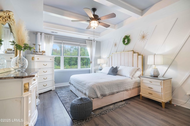 bedroom with a tray ceiling, dark wood-type flooring, and ceiling fan