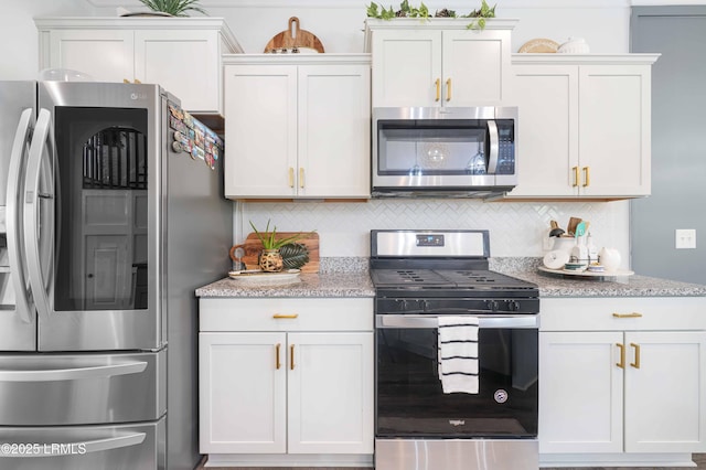 kitchen with decorative backsplash, white cabinets, and appliances with stainless steel finishes