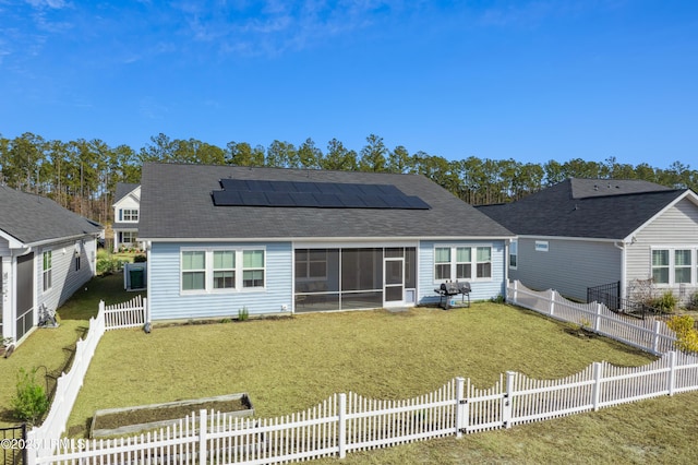 back of house with a yard, a sunroom, and solar panels