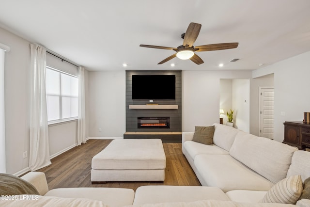 living room with hardwood / wood-style flooring, ceiling fan, and a fireplace