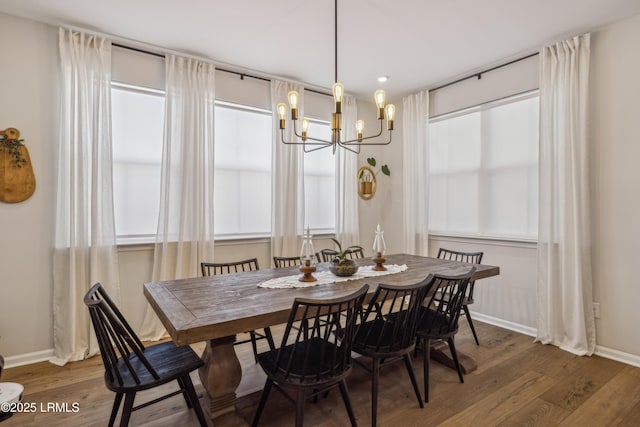 dining room with dark wood-type flooring and an inviting chandelier