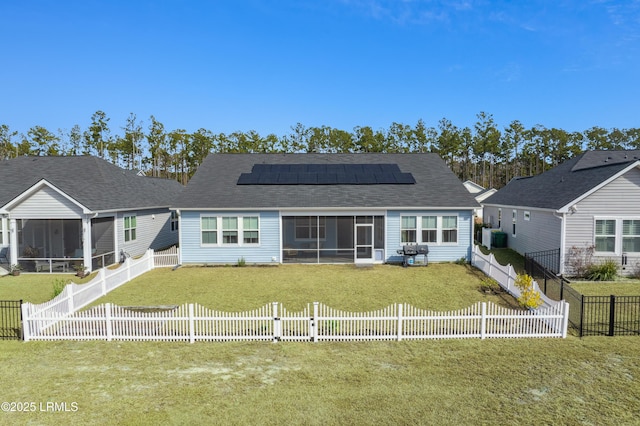 rear view of house featuring a yard, a sunroom, and solar panels