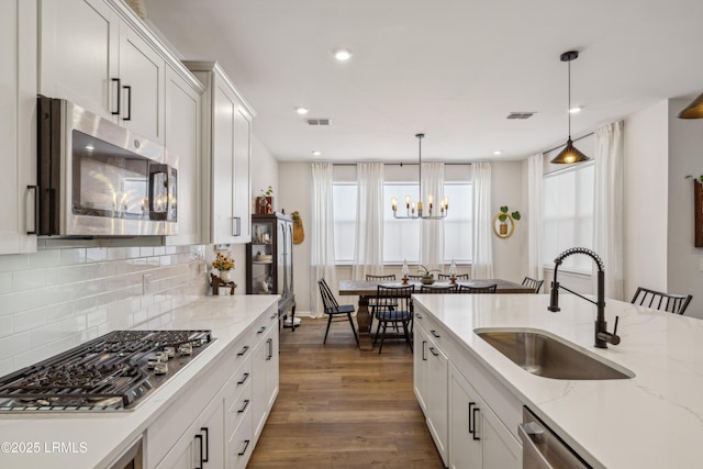 kitchen with dark hardwood / wood-style floors, decorative light fixtures, white cabinetry, sink, and stainless steel appliances