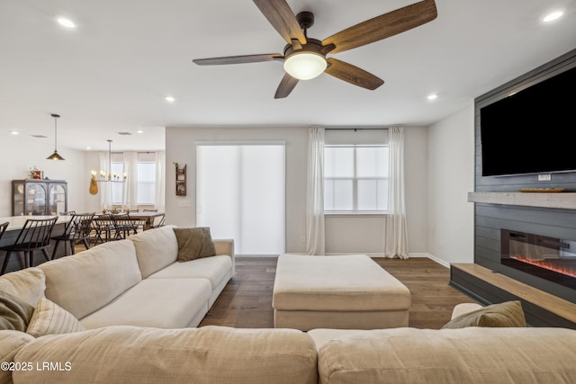 living room featuring plenty of natural light, a fireplace, dark hardwood / wood-style flooring, and ceiling fan with notable chandelier