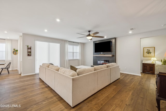 living room featuring a fireplace, wood-type flooring, and ceiling fan