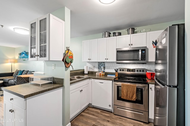 663 William Hilton Pkwy Unit 3404, Hilton Head Island, SC 29928 - kitchen with stainless steel appliances, dark countertops, dark wood-style floors, white cabinetry, and glass insert cabinets