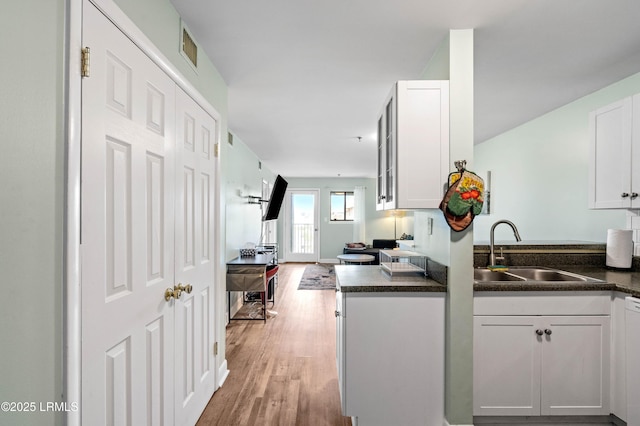 663 William Hilton Pkwy Unit 3404, Hilton Head Island, SC 29928 - kitchen with a sink, dark countertops, light wood-style flooring, white cabinetry, and open floor plan