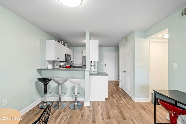 663 William Hilton Pkwy Unit 3404, Hilton Head Island, SC 29928 - kitchen with light wood finished floors, stainless steel microwave, white cabinetry, and baseboards