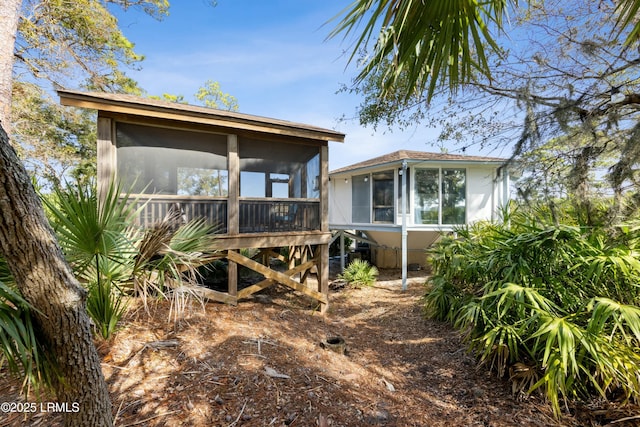 rear view of property with a sunroom and stucco siding