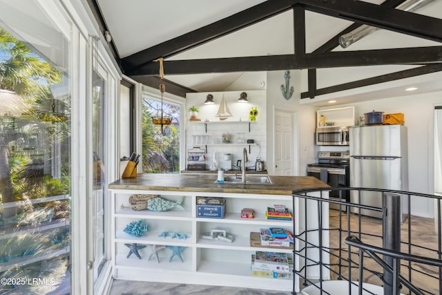 kitchen with stainless steel appliances, a sink, and lofted ceiling with beams