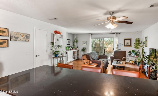 living room featuring ceiling fan, a textured ceiling, and light wood-type flooring