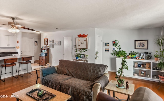 living room with ceiling fan, dark hardwood / wood-style floors, and a textured ceiling