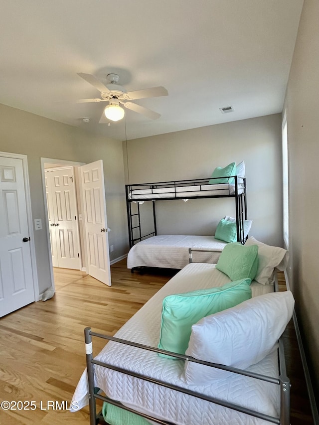 bedroom with ceiling fan, baseboards, wood finished floors, and visible vents