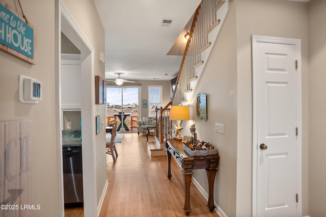 hall with stairway, baseboards, light wood-style floors, and visible vents