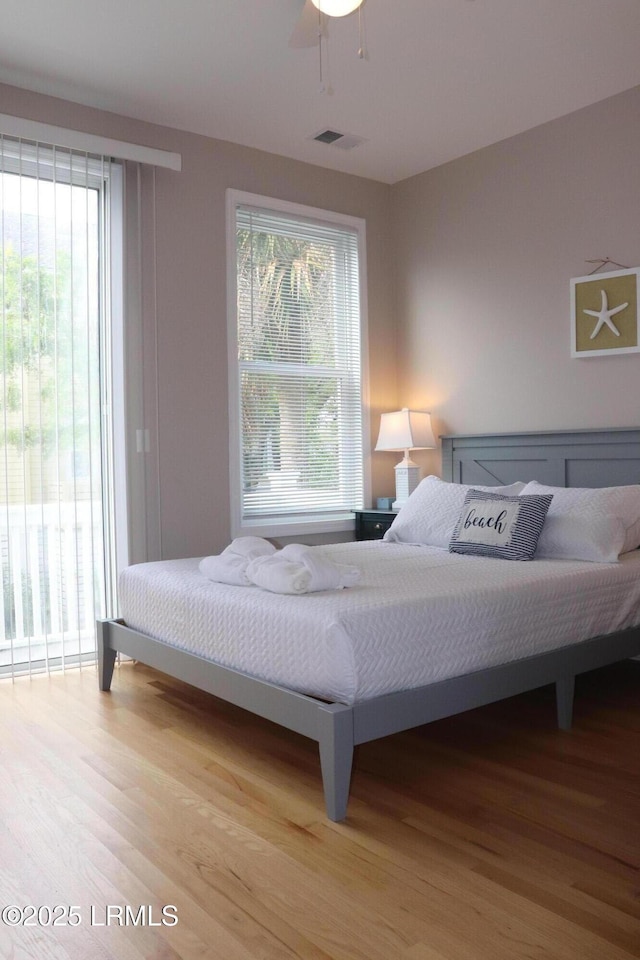 bedroom featuring wood finished floors, visible vents, ceiling fan, and multiple windows