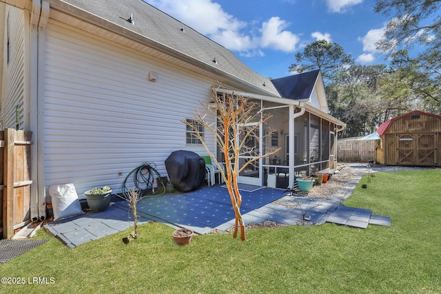 back of property featuring a patio, fence, a sunroom, a lawn, and a shed