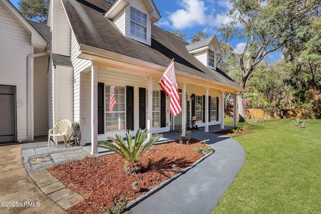 view of front of house featuring a front yard, roof with shingles, and fence