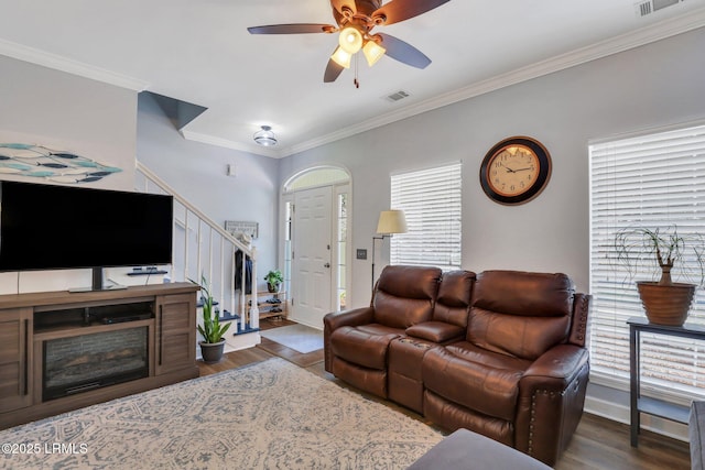 living area with dark wood-style floors, stairs, visible vents, and ornamental molding