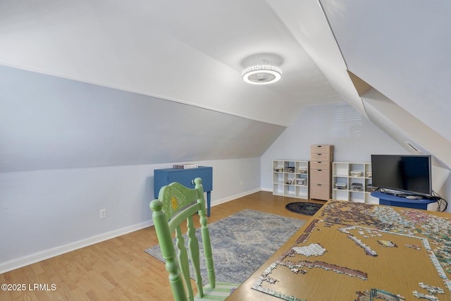 interior space featuring vaulted ceiling, baseboards, and wood finished floors