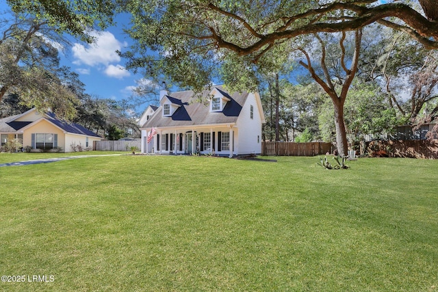 new england style home featuring covered porch, fence, and a front yard