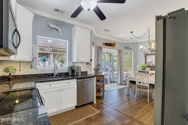 kitchen featuring hanging light fixtures, appliances with stainless steel finishes, a sink, and white cabinets