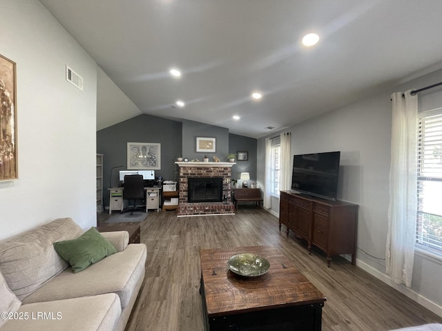 living room with a wealth of natural light, lofted ceiling, and hardwood / wood-style floors