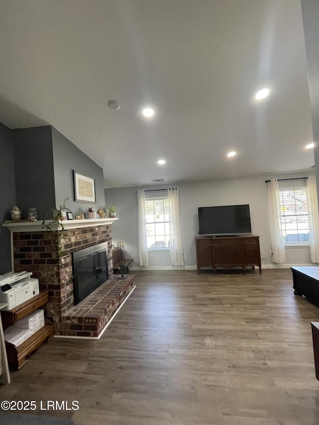 living room with lofted ceiling, hardwood / wood-style floors, and a brick fireplace