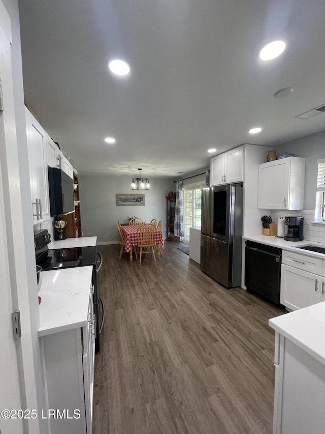 kitchen featuring tasteful backsplash, hardwood / wood-style floors, white cabinets, and black appliances