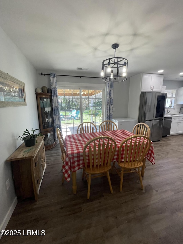 dining space featuring dark hardwood / wood-style flooring, sink, a notable chandelier, and plenty of natural light