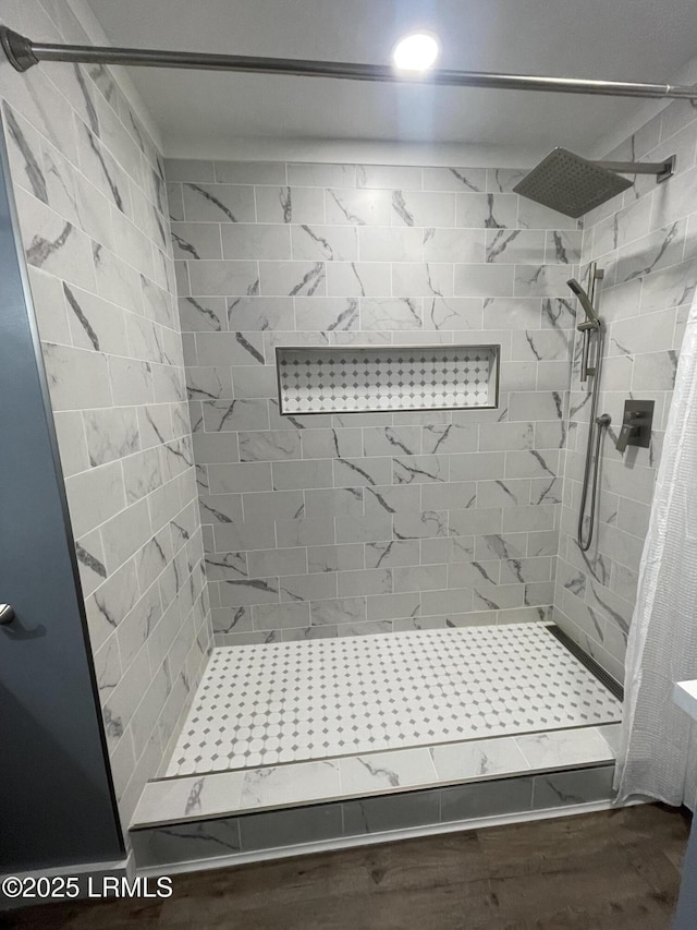 bathroom featuring hardwood / wood-style flooring and tiled shower