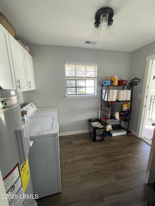 washroom featuring cabinets, electric water heater, washing machine and clothes dryer, and dark hardwood / wood-style flooring