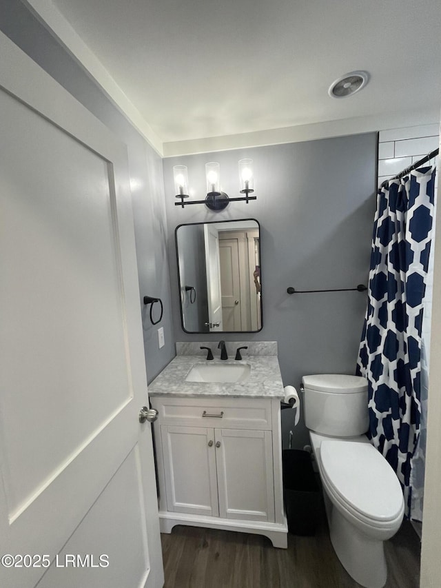 bathroom featuring vanity, curtained shower, wood-type flooring, and toilet