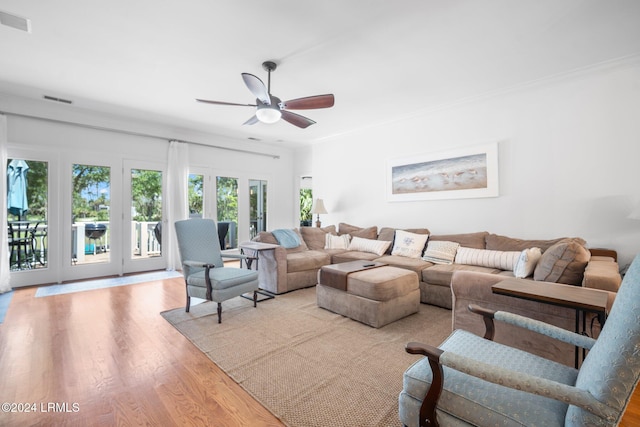 living room with crown molding, ceiling fan, and light wood-type flooring