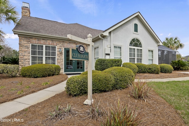 1034 Abbey Glen Way, Hardeeville, SC 29927 - view of front facade featuring roof with shingles, a chimney, stone siding, and stucco siding