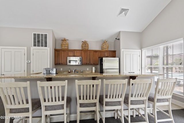 1034 Abbey Glen Way, Hardeeville, SC 29927 - kitchen with a breakfast bar area, stainless steel appliances, visible vents, and brown cabinetry