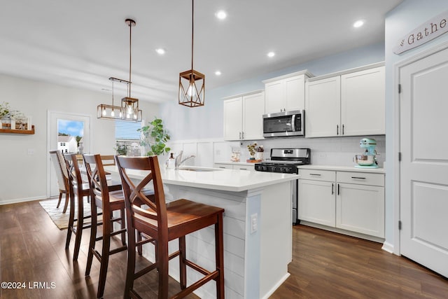 kitchen featuring pendant lighting, appliances with stainless steel finishes, sink, and white cabinets