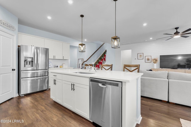 kitchen featuring sink, stainless steel appliances, white cabinets, a center island with sink, and decorative light fixtures