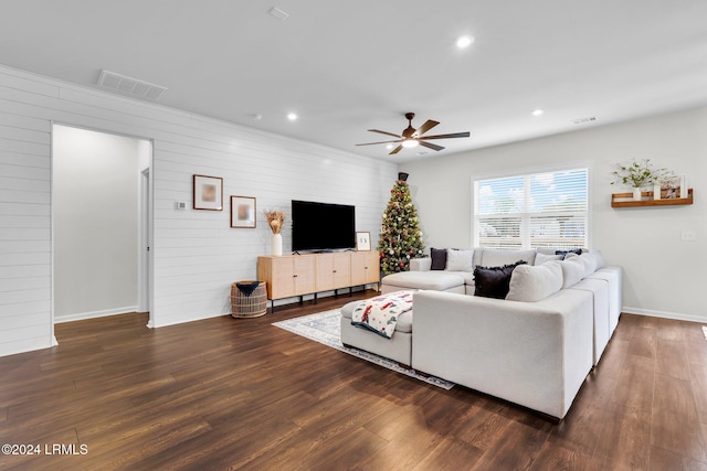 living room featuring ceiling fan, dark hardwood / wood-style flooring, and wood walls